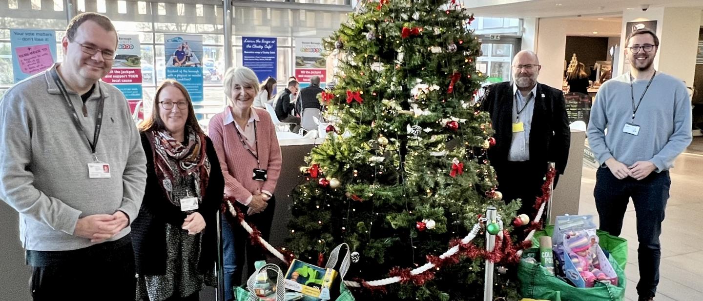 Leader and Deputy Leader of Havant Borough Council, Chief Executive Matt Goodwin, and Outreach Workers Chris and Suzie standing around a Christmas tree with gifts underneath
